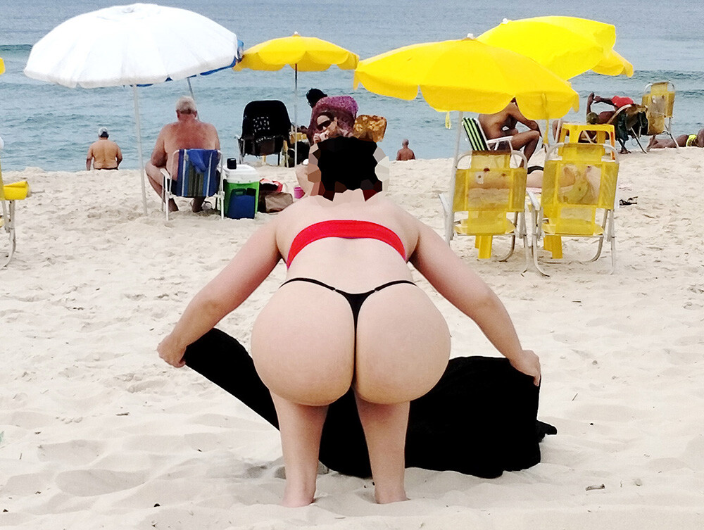 Big-bootied wife crouching down, adjusting her sarong on the ground in full view of everyone on the beach